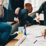 Grupo de estudantes reunidas em uma atividade escolar, estudando e fazendo anotações com canetas coloridas.
